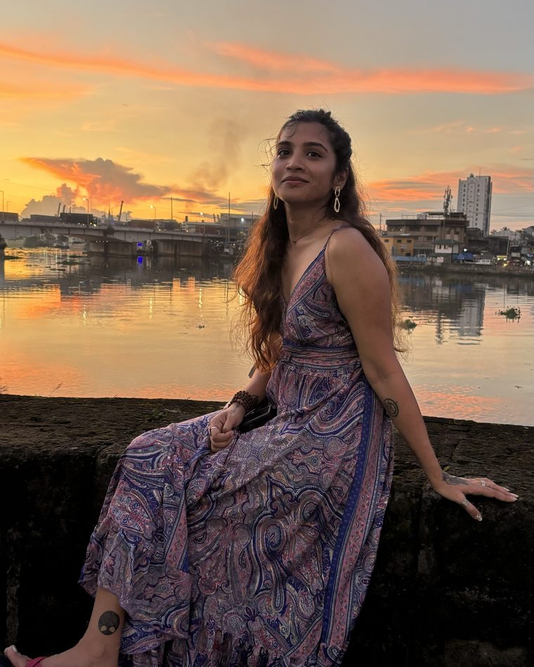 Madhulatha Palli sitting by the water at sunset